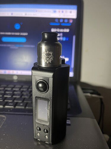 Egy fekete vape eszköz áll egy laptop billentyűzete előtt, a laptop képernyője hátul világít. (Feliratozva AI-val)
