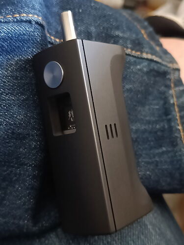 Egy fekete, kézben tartott elektromos cigaretta vagy vaporizátor van farmernadrágon nyugalmi állapotban. (Feliratozva AI-val)
