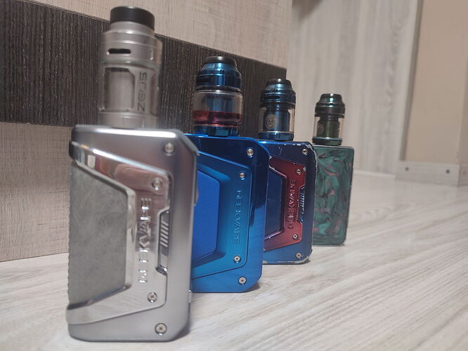 Négy különböző színű és dizájnú vape készülék sorakozik egy fa felületen. {vape, mods, vaping} (Feliratozva AI-val)