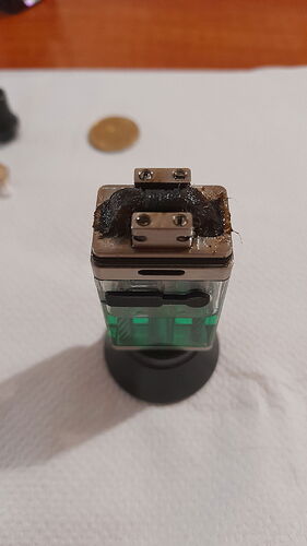 Egy elektronikus cigaretta vagy vape alkatrész égett maradvánnyal a tetején, fehér felületen pihen. (Feliratozva AI-val)