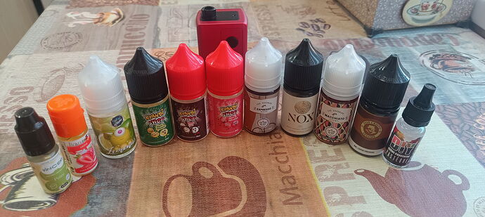Különféle e-liquid flakonok és egy piros e-cigaretta eszköz láthatók egy mintás asztalon. (Feliratozva AI-val)