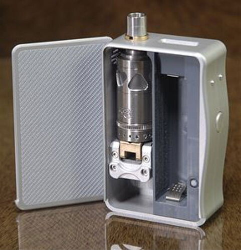 Egy nyitott, ezüst színű vape mod látható belső részeivel és egy fémes tartállyal, mely egy fa felületen áll. (Feliratozva AI-val)
